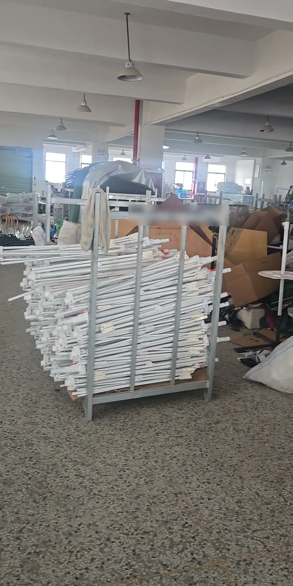 Umbrella frames stacked in carts with the workshop behind them