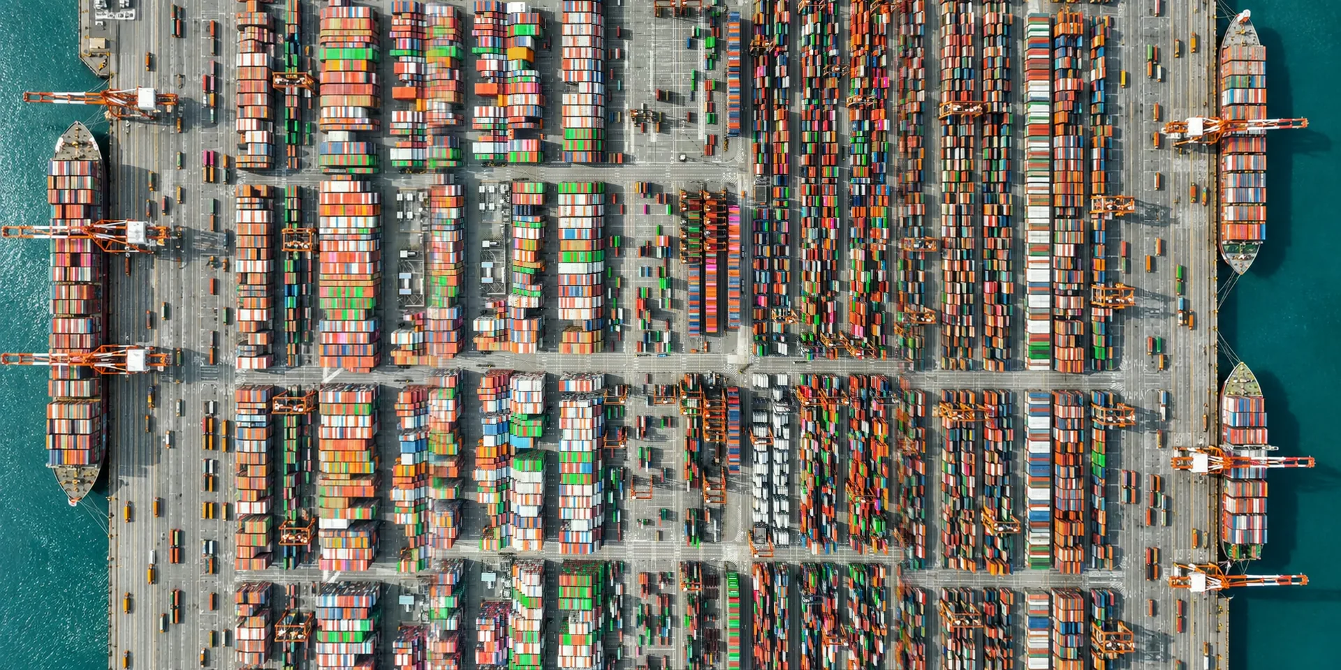 Rows of coloured shipping containers in a port yard, seen from above